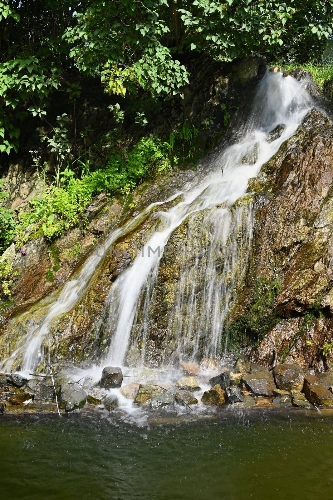 Beautiful small waterfall with a rock in nature. Brno castle Spilberk.