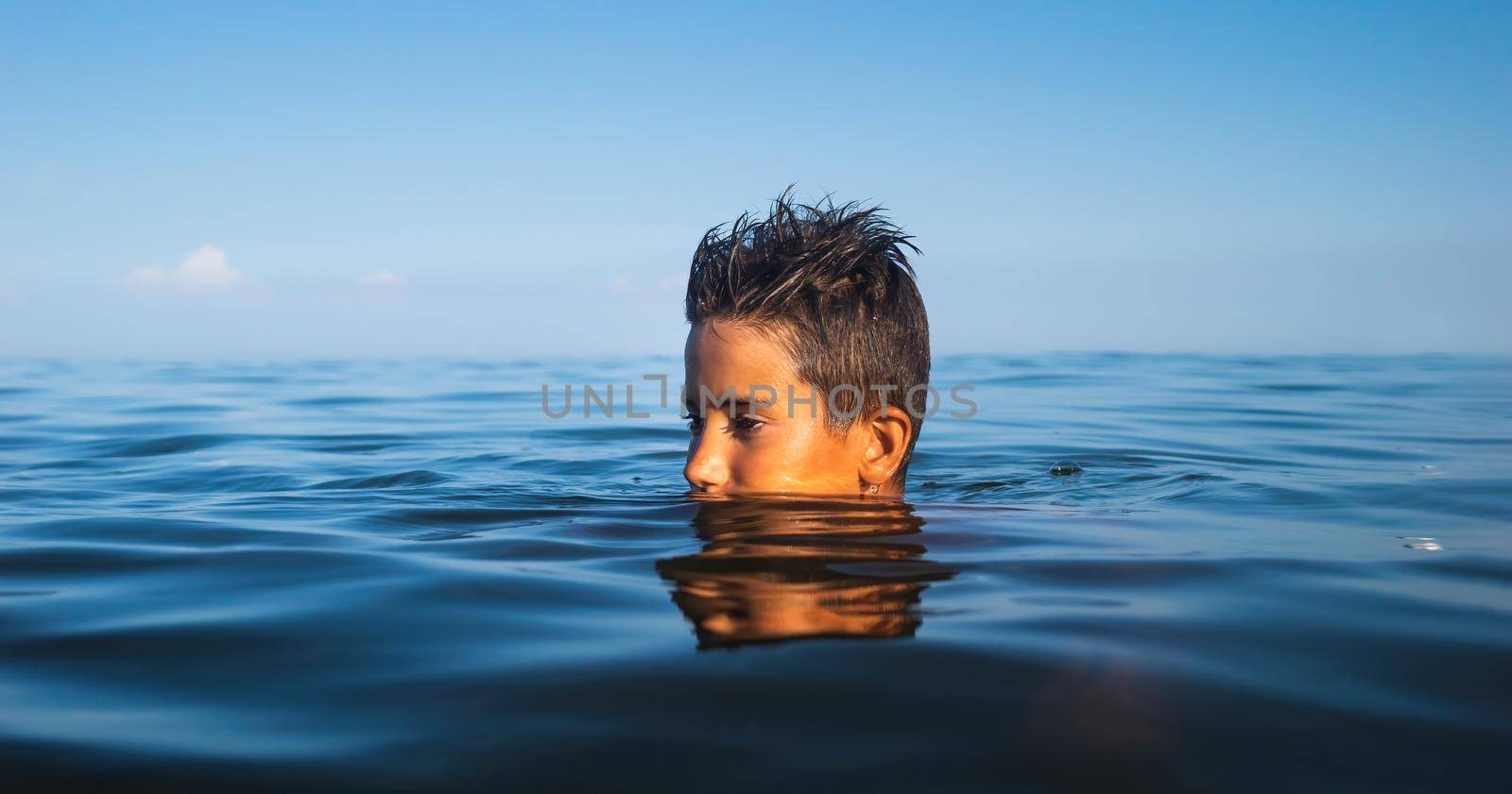 Relaxation and healthy lifestyle. Young boy teenager bathes in the sea.