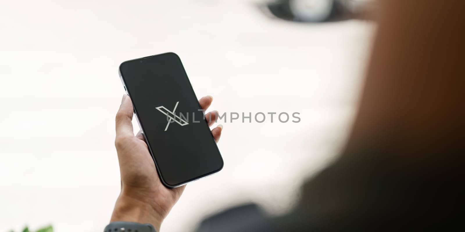 CHIANG MAI, THAILAND- JULY 26, 2023 : Man using iPhone open Twitter application showing X new logo, online social networking and service that enables users to send and read messages..