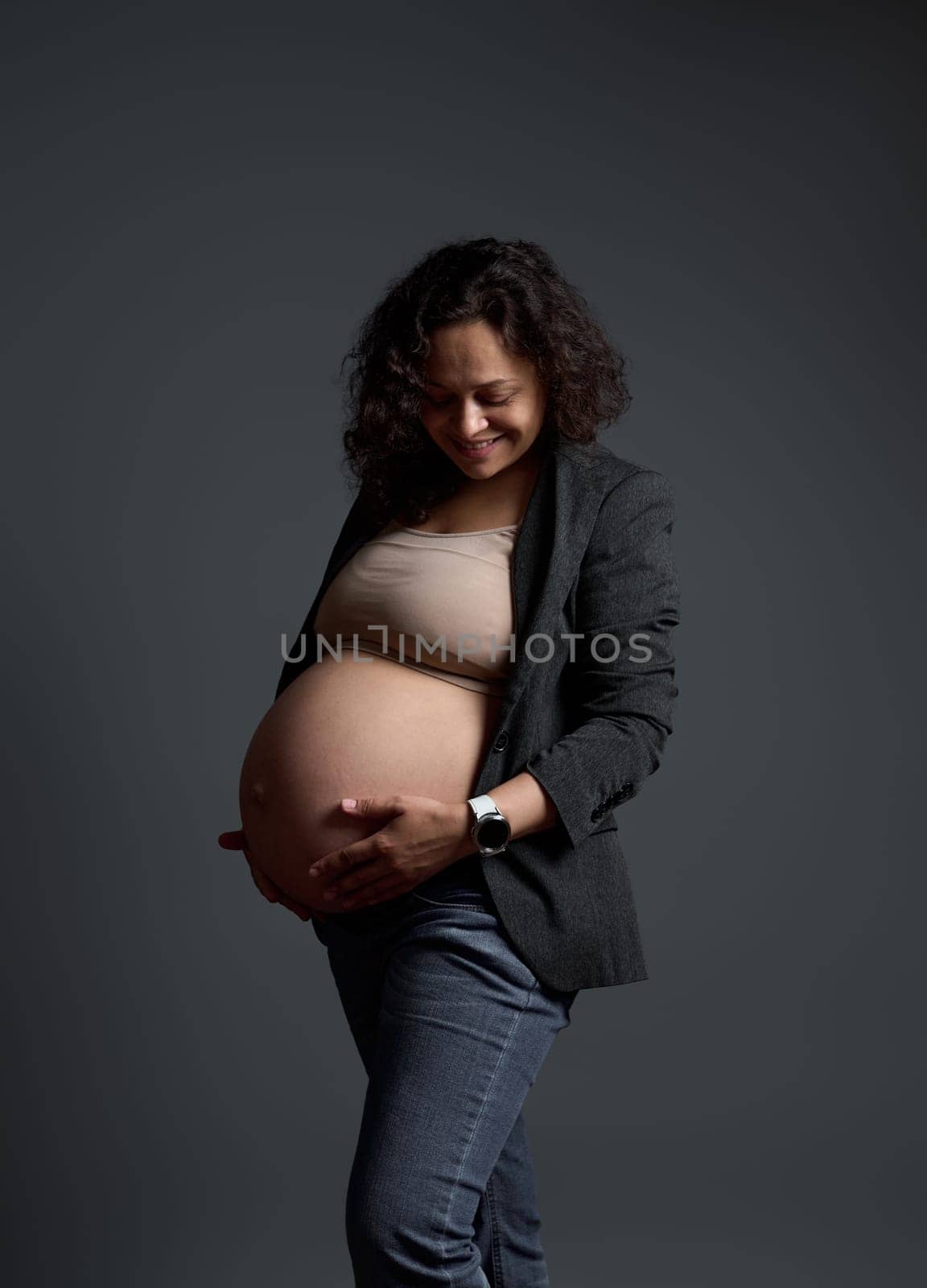 Smiling pregnant woman expecting baby, experiencing positive emotions feeling baby moves, isolated gray background