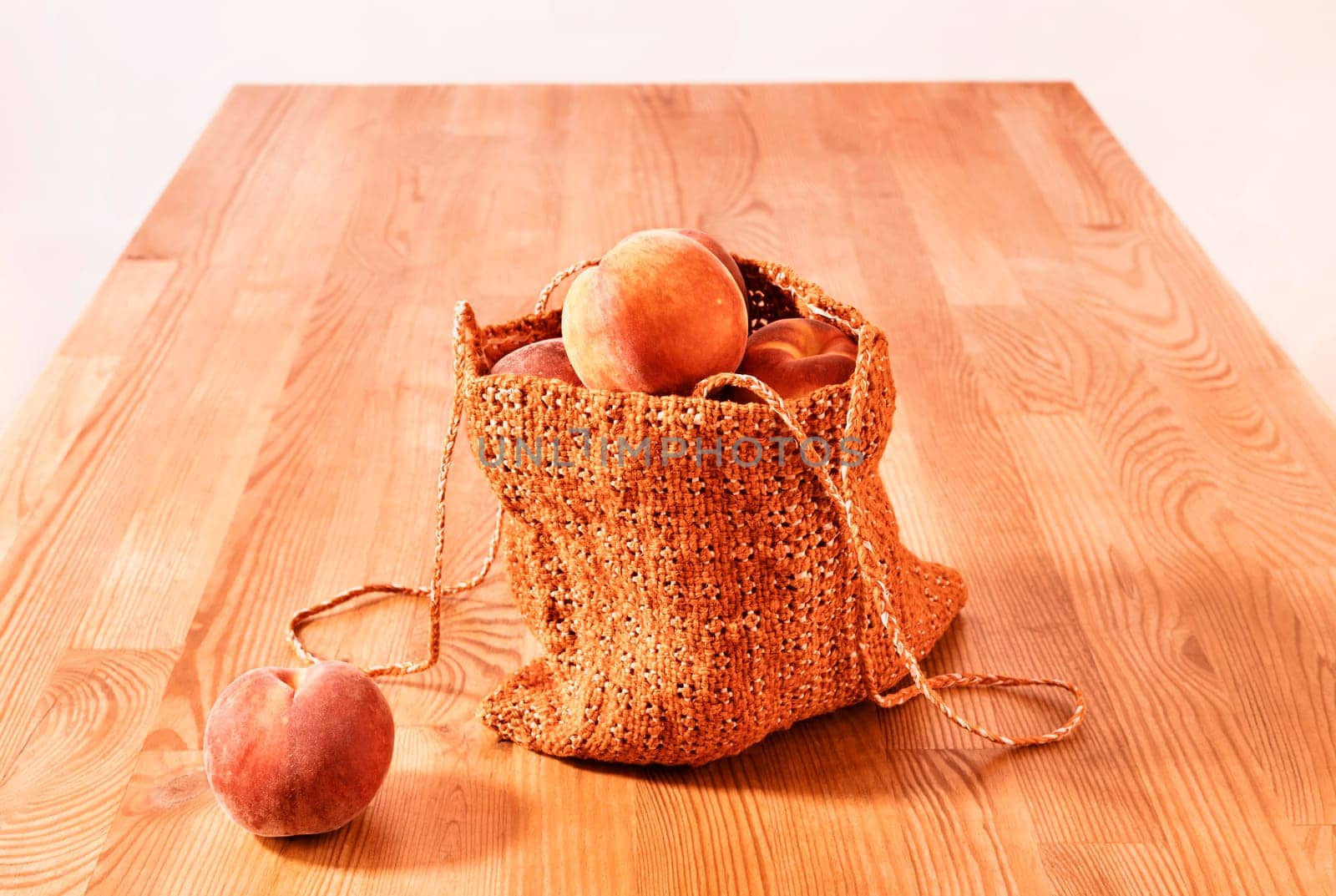 Ripe fruit of peaches in orange shopping bag on wooden table , 
