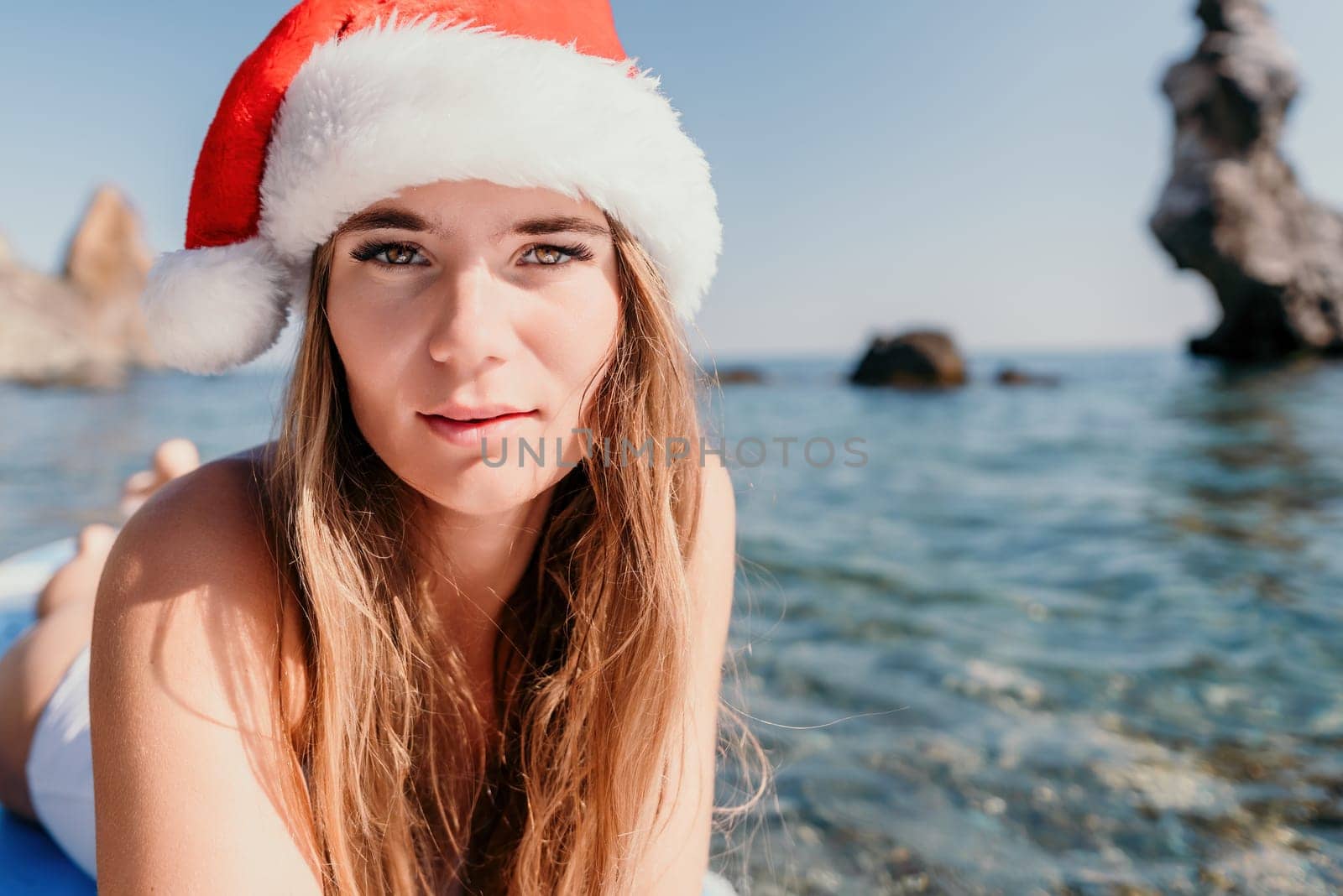 Close up shot of happy young caucasian woman looking at camera and smiling. Cute woman portrait in bikini posing on a volcanic rock high above the sea