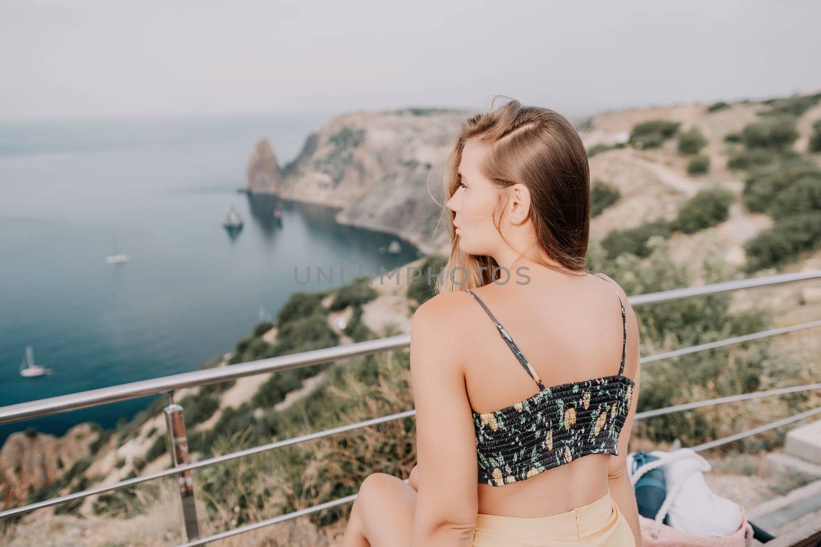 Woman travel sea. Happy tourist enjoy taking picture outdoors for memories. Woman traveler looks at the edge of the cliff on the sea bay of mountains, sharing travel adventure journey by panophotograph