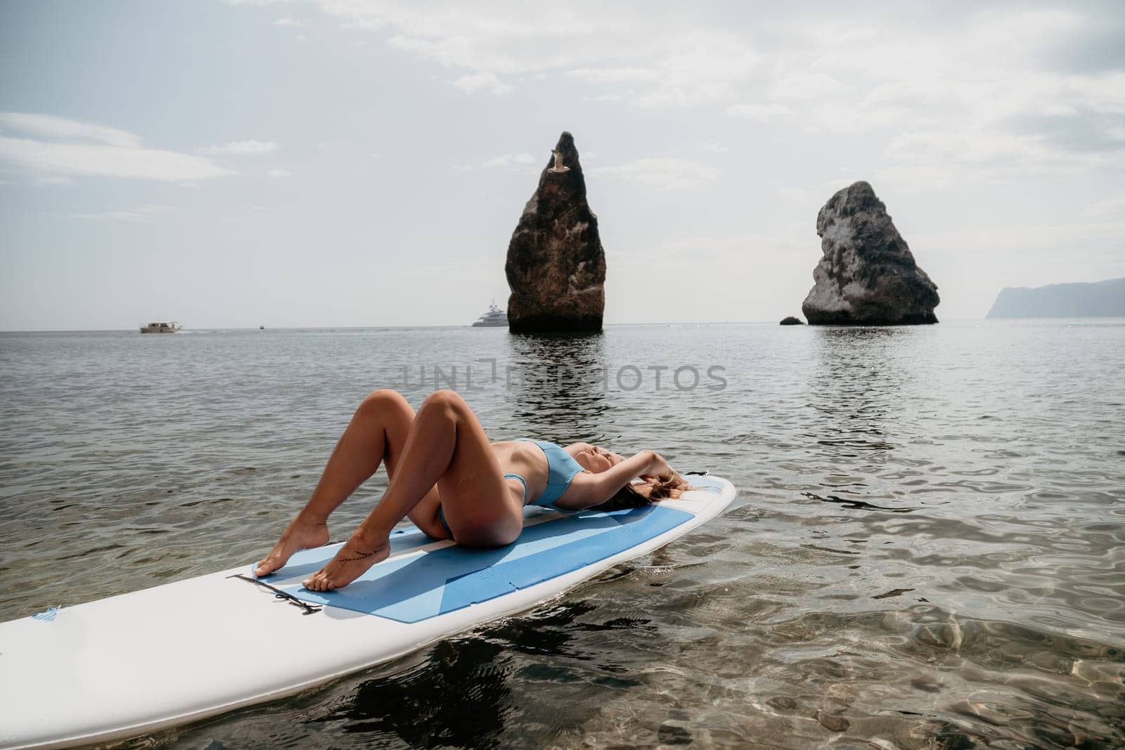 Woman sea sup. Close up portrait of happy young caucasian woman with long hair looking at camera and smiling. Cute woman portrait in bikini posing on sup board in the sea by panophotograph