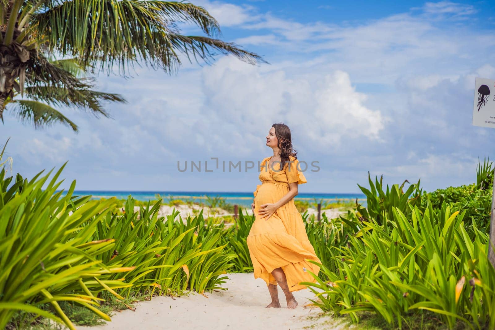 A radiant pregnant woman after 40 basking in the sun's warmth on a tropical beach, cherishing the serenity and bliss of her pregnancy journey.