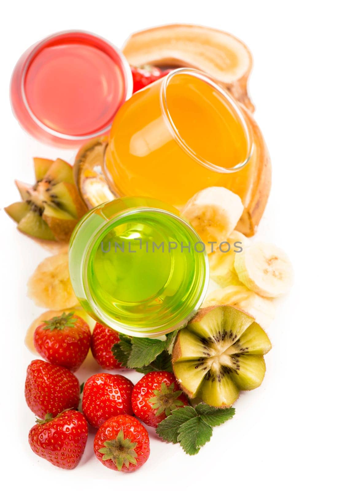 banana , kiwi and strawberry jelly in glasses with fresh berries and fruits on a white background by aprilphoto