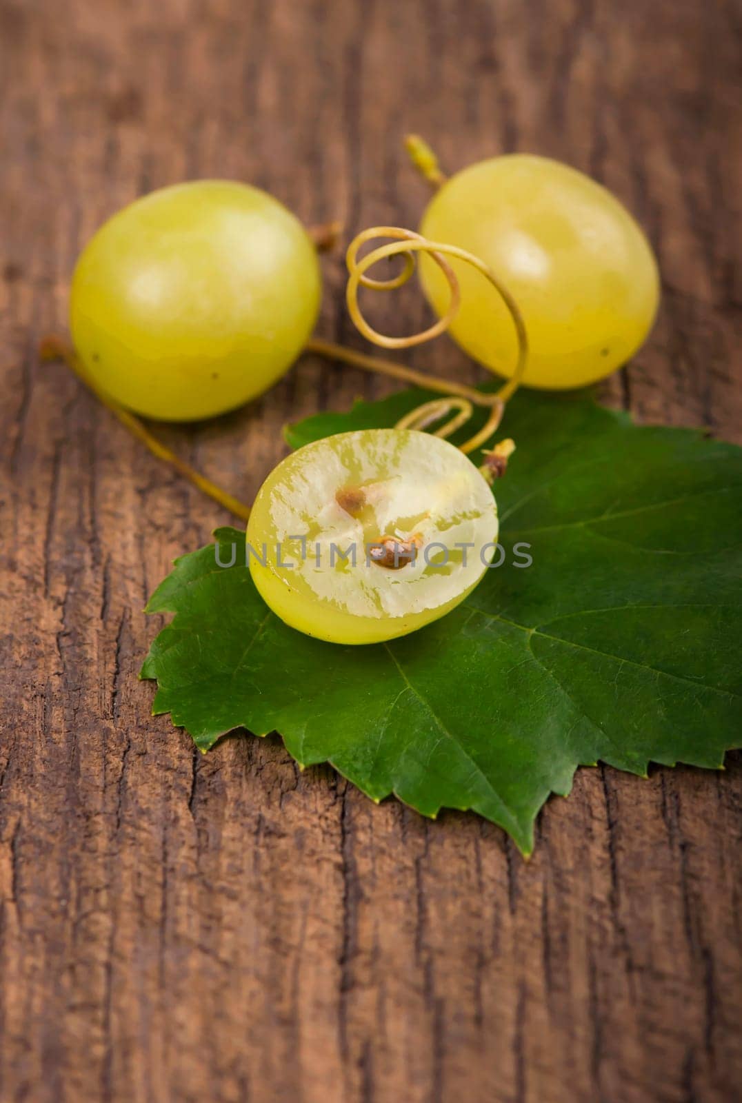 Juicy green grapes - macro shot of whole and cut berries on wooden background
