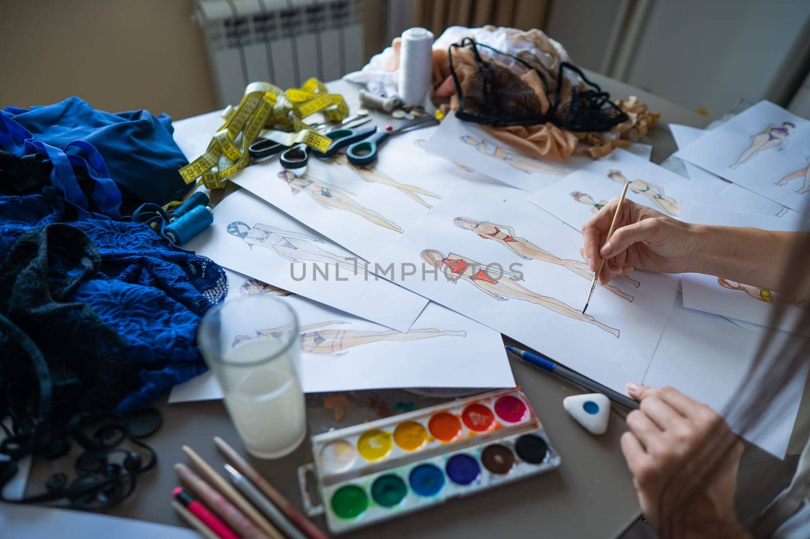 Woman drawing sketches of swimwear and underwear in watercolor