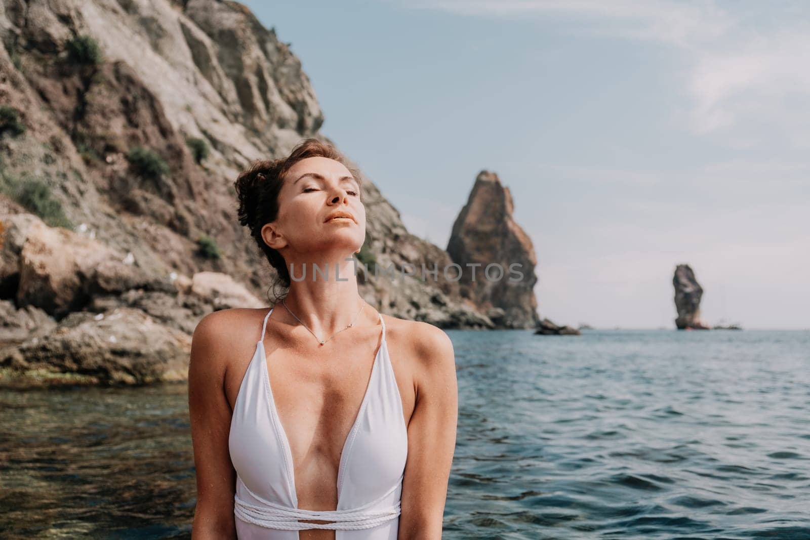 Woman sea fitness. Happy woman in a white bikini performing pilates in the sea on the beach. Female fitness yoga routine concept. Healthy lifestyle. by panophotograph