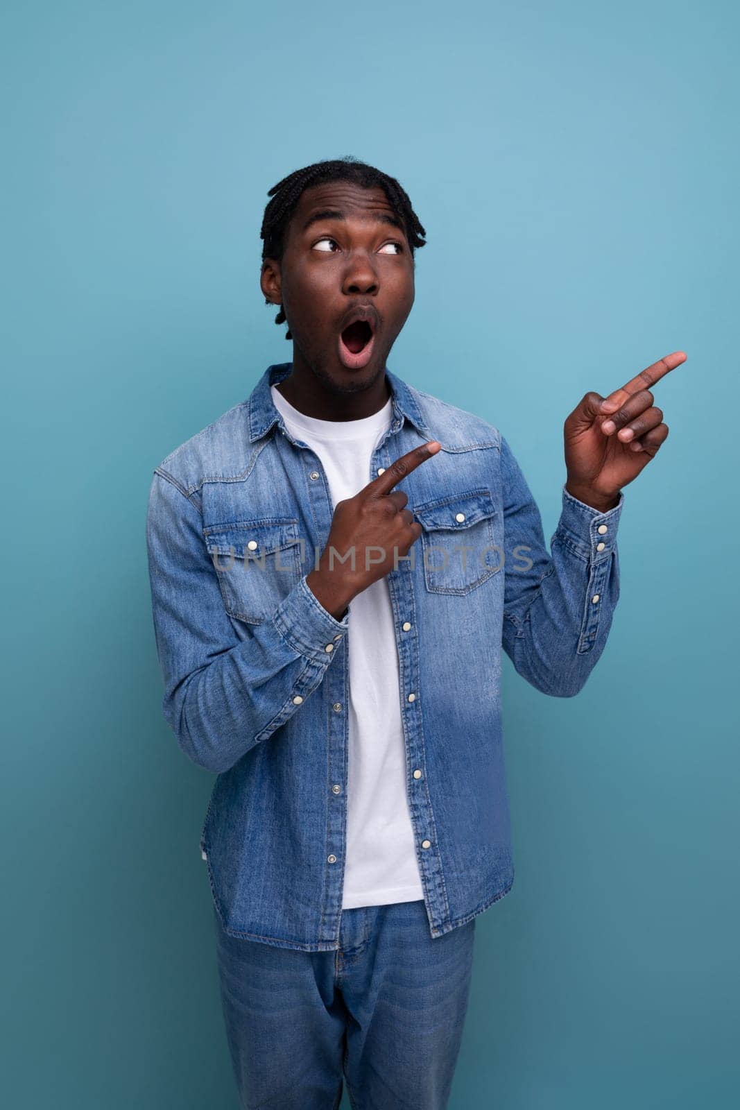 charismatic stylish african man with black dreadlocks points finger to the side.