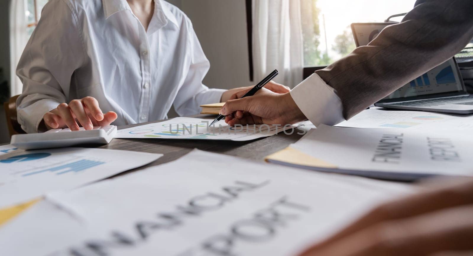 Teamwork of business two colleagues analysis with financial data and marketing report graph, Young business woman two co worker discussing for calculating financial document with calculator.