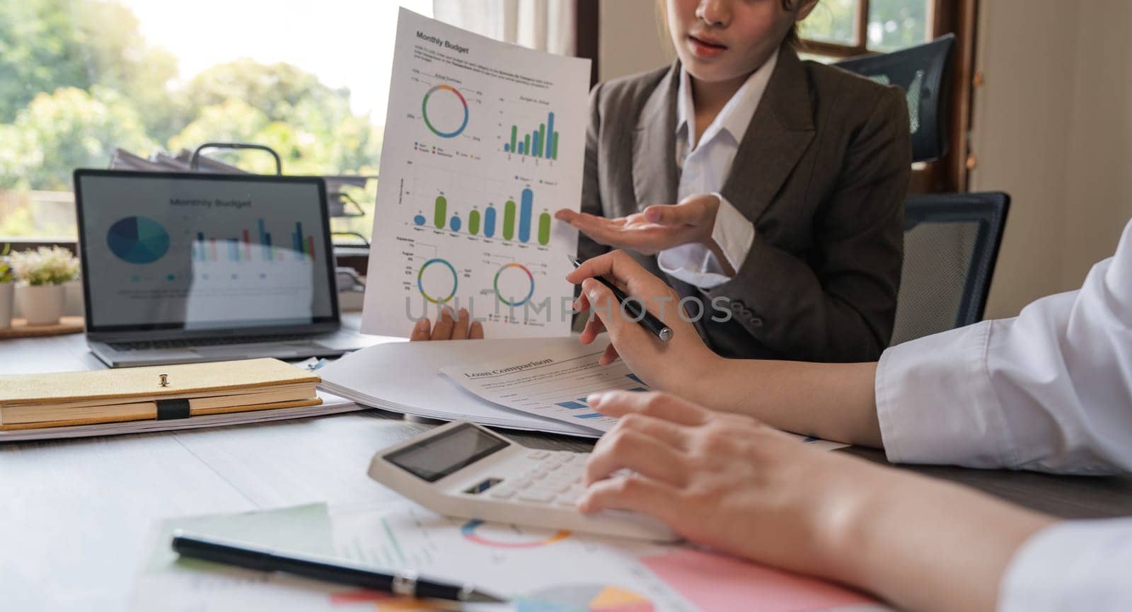 Teamwork of business two colleagues analysis with financial data and marketing report graph, Young business woman two co worker discussing for calculating financial document with calculator.