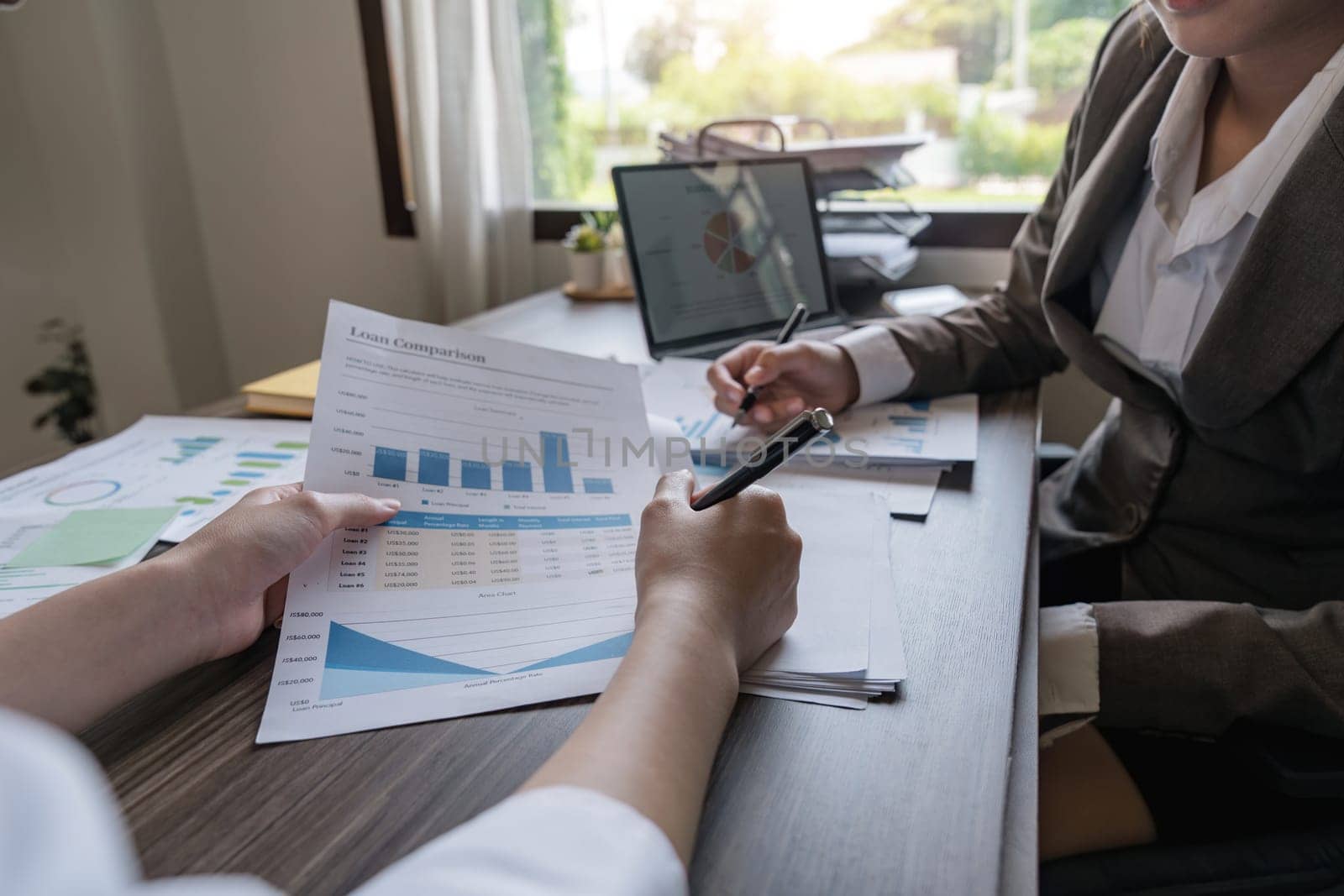 Two Asian business women Discussing Financial reports, analytical concepts, planning and financial statistics and investment markets at the office.