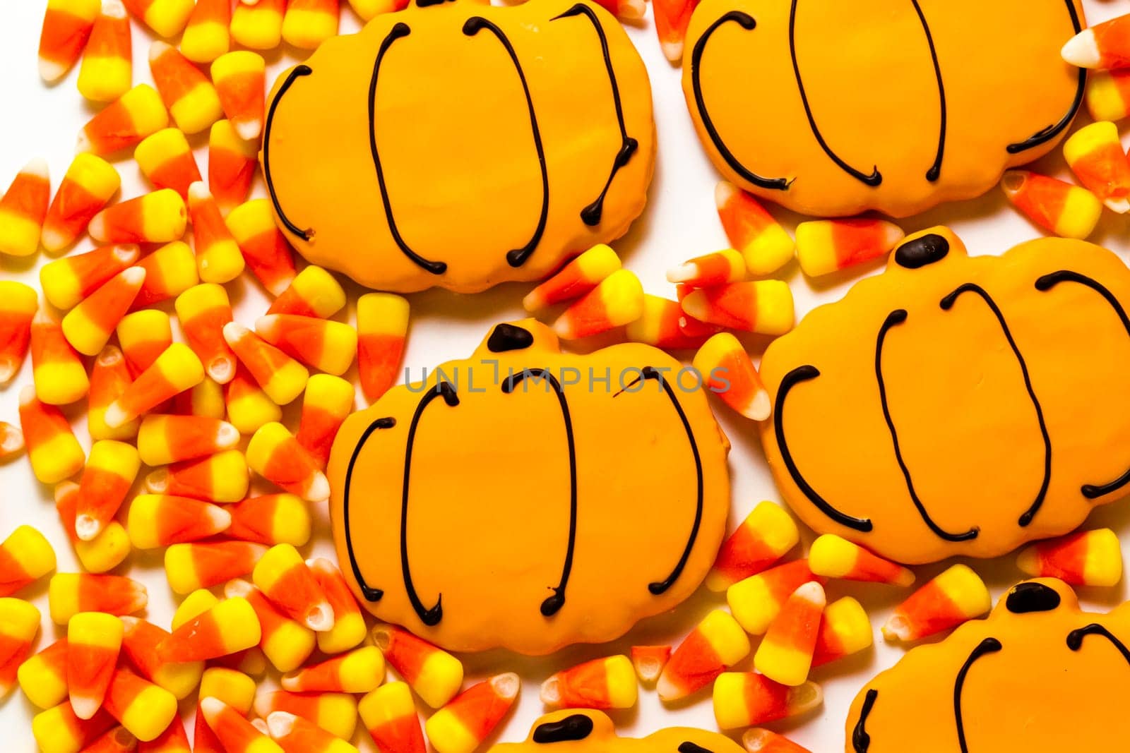 Sugar cookies with orange icing shaped like a pumpkin.