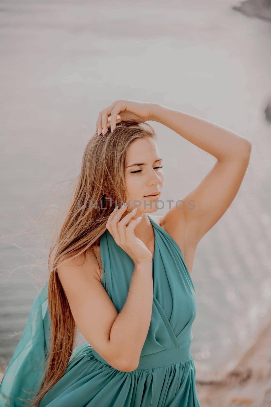 Woman sea green dress. Portrait of a happy woman with long hair in a long mint dress posing on a beach with calm sea bokeh lights on sunny day. Girl on the nature on blue sky background