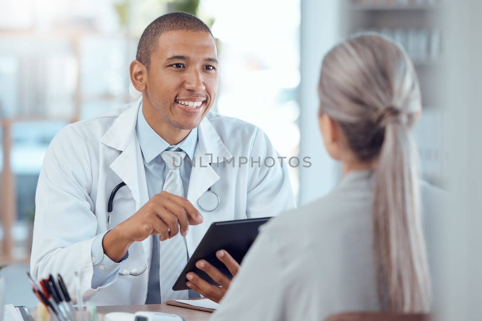 Tablet, office and doctor consulting a patient in a health conversation or communication during medical consultation. Medicine, healthcare and professional talking to person for results in a clinic by YuriArcurs