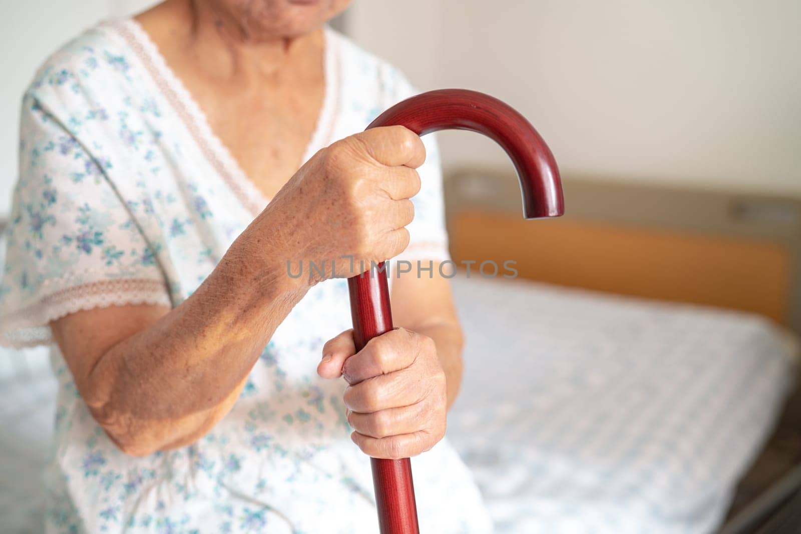 Asian elderly disability woman holding waling stick, wood cane, round handle, walking aid for help to walk. by pamai