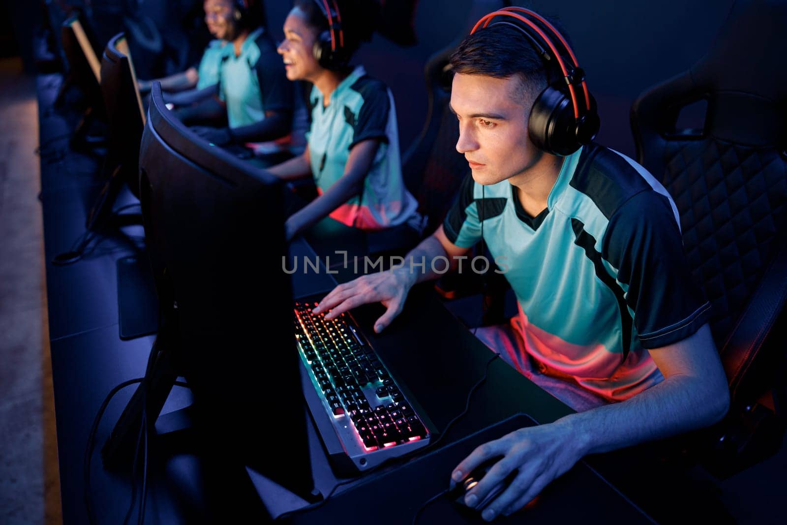Young esports player concentrated on game wearing wired headset while playing online multiplayer game in cyber club