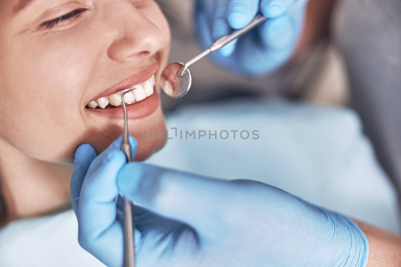 Confident mature doctor is checking teeth of young beautiful happy caucasian woman in modern clinic