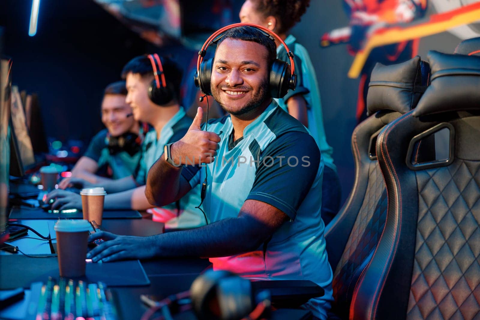 Happy young man expressing satisfaction with game while giving thumbs up gesture during participation in international gaming event in gaming club