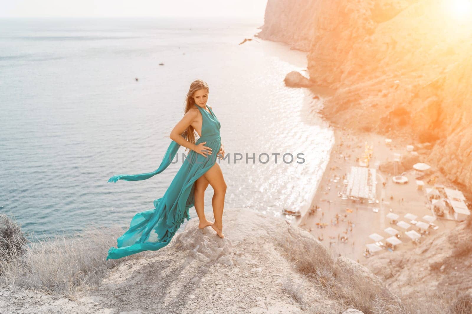 Woman sea trevel green dress. Side view a happy woman with long hair in a long mint dress posing on a beach with calm sea bokeh lights on sunny day. Girl on the nature on blue sky background