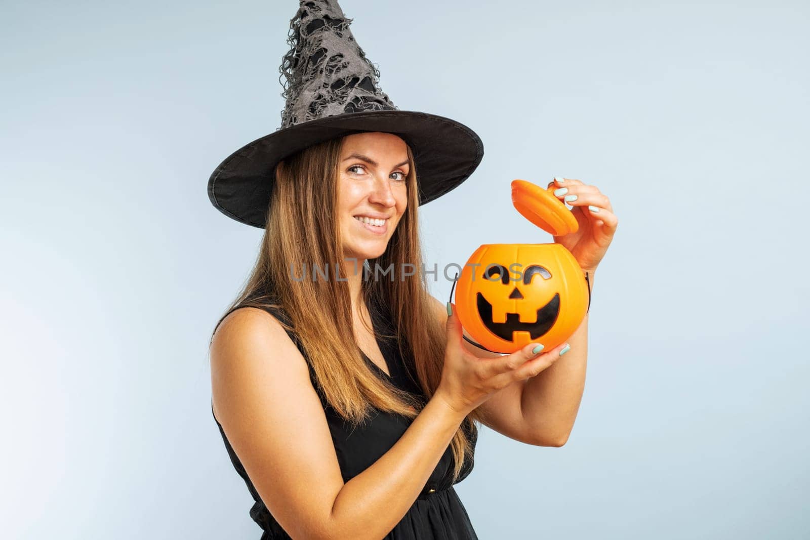 Happy Halloween. Happy young woman in halloween witch costume with pumpkin basket jack-o-lantern.