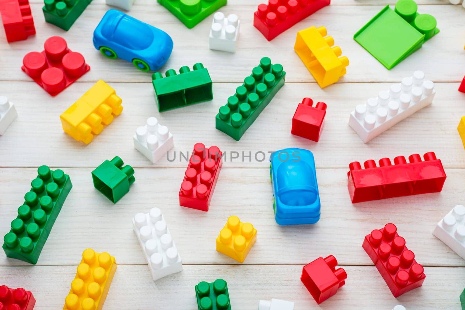 Colorful plastic toy blocks. Colorful plastic toy blocks on white wooden background. Top view. Baby background