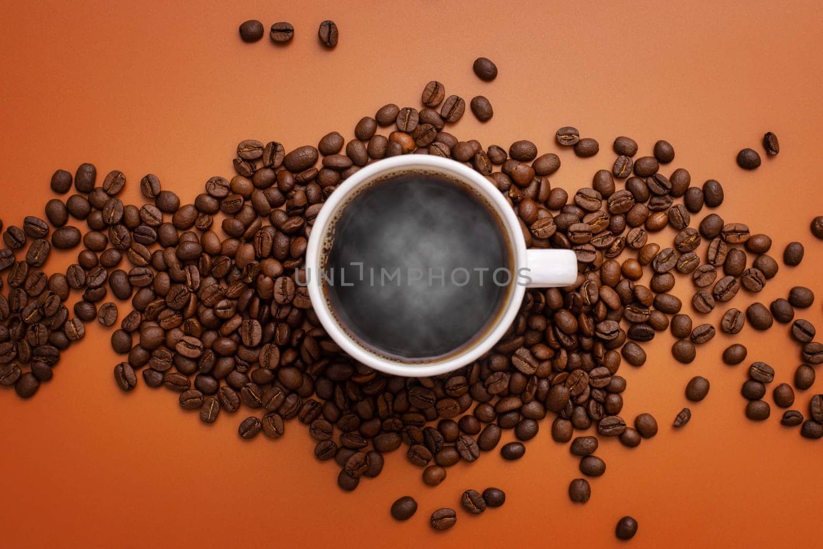 Warm cup of coffee and coffee beans on brown background. Coffee cup and coffee beans on the table.