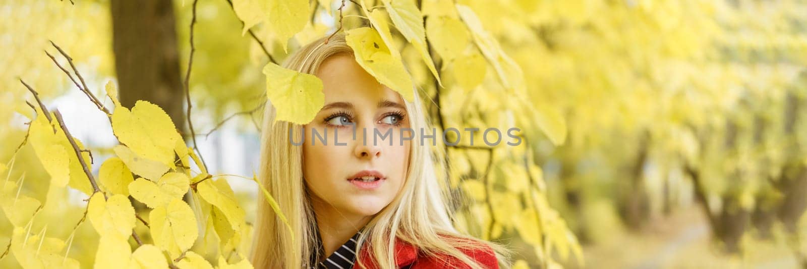 A young blonde woman walks around the autumn city in a red coat. The concept of urban style and lifestyle. Autumn portrait. by Annu1tochka