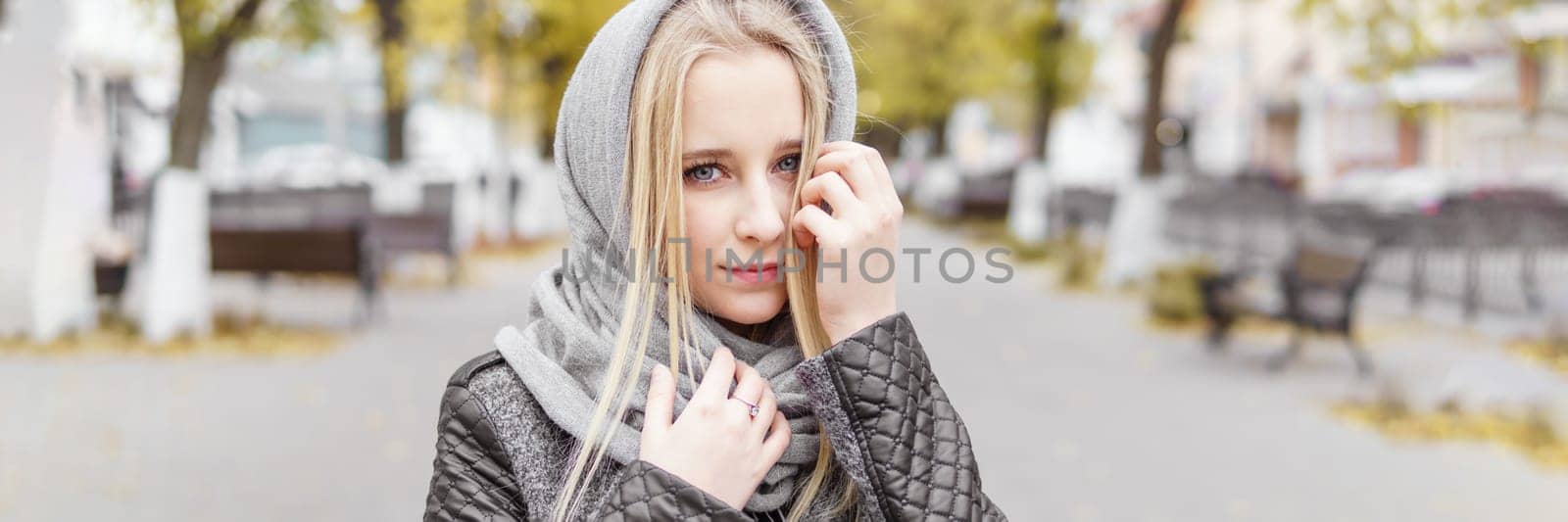 A young blonde walks through the autumn city in a gray coat. The concept of urban style and lifestyle