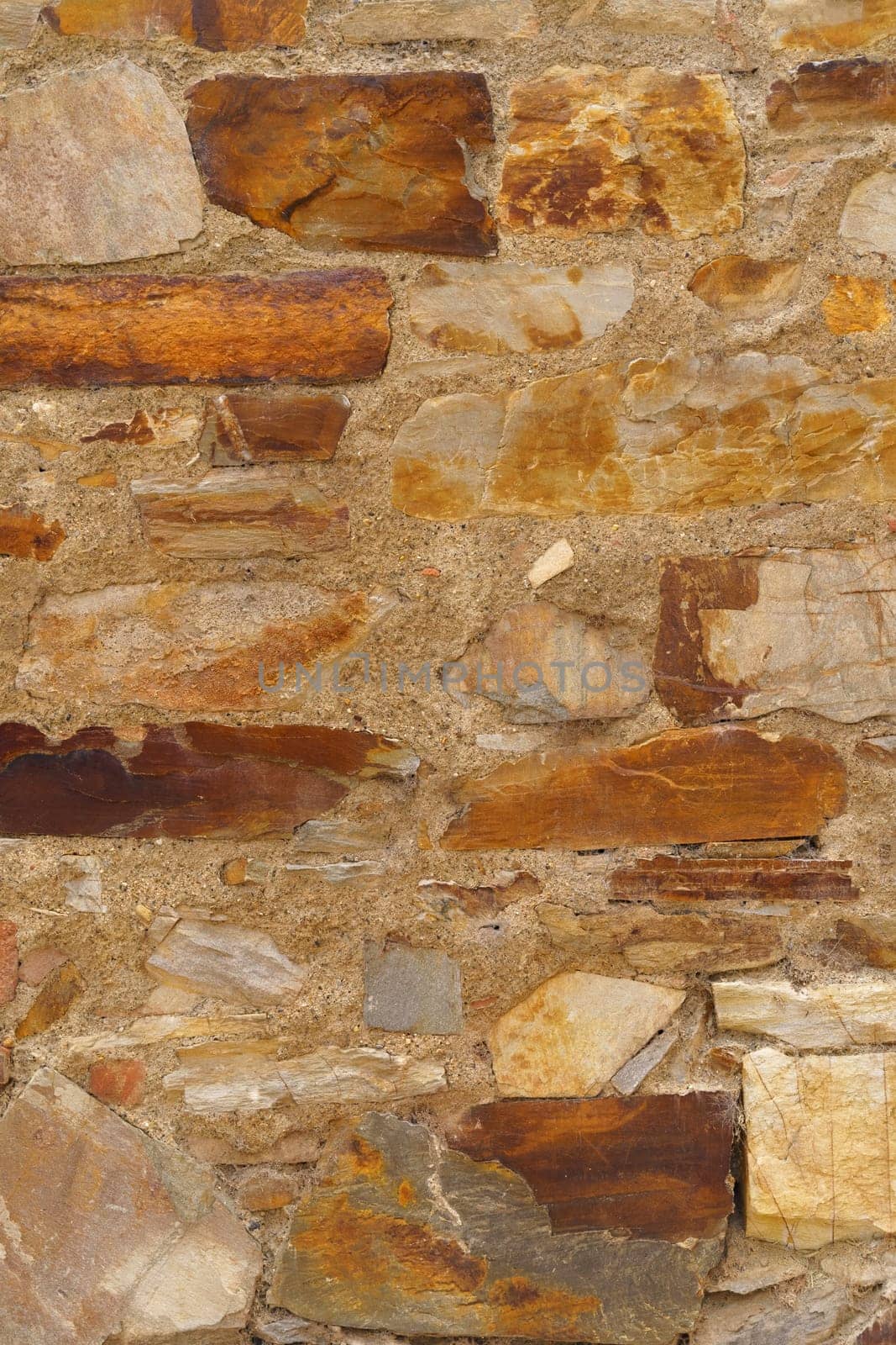 The texture of the old medieval wall of the house, lined with brown stone. Vertical frame.