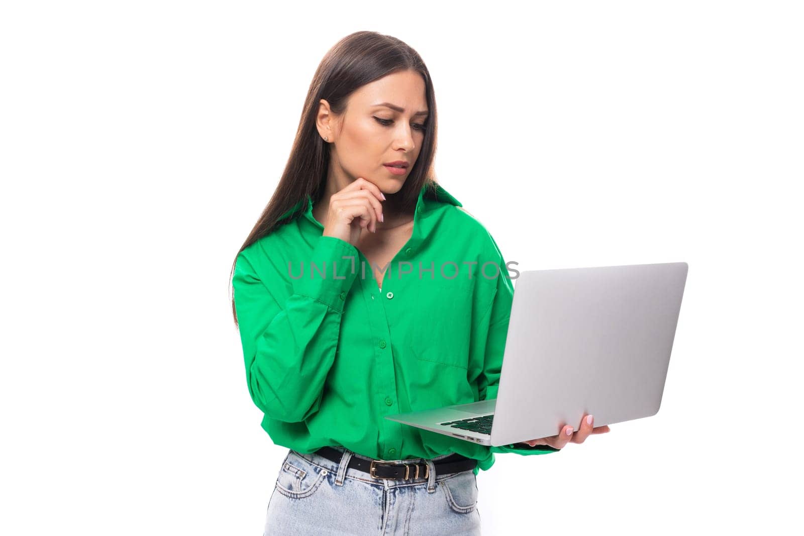 young european brunette woman with brown eyes in green blouse works online using laptop by TRMK