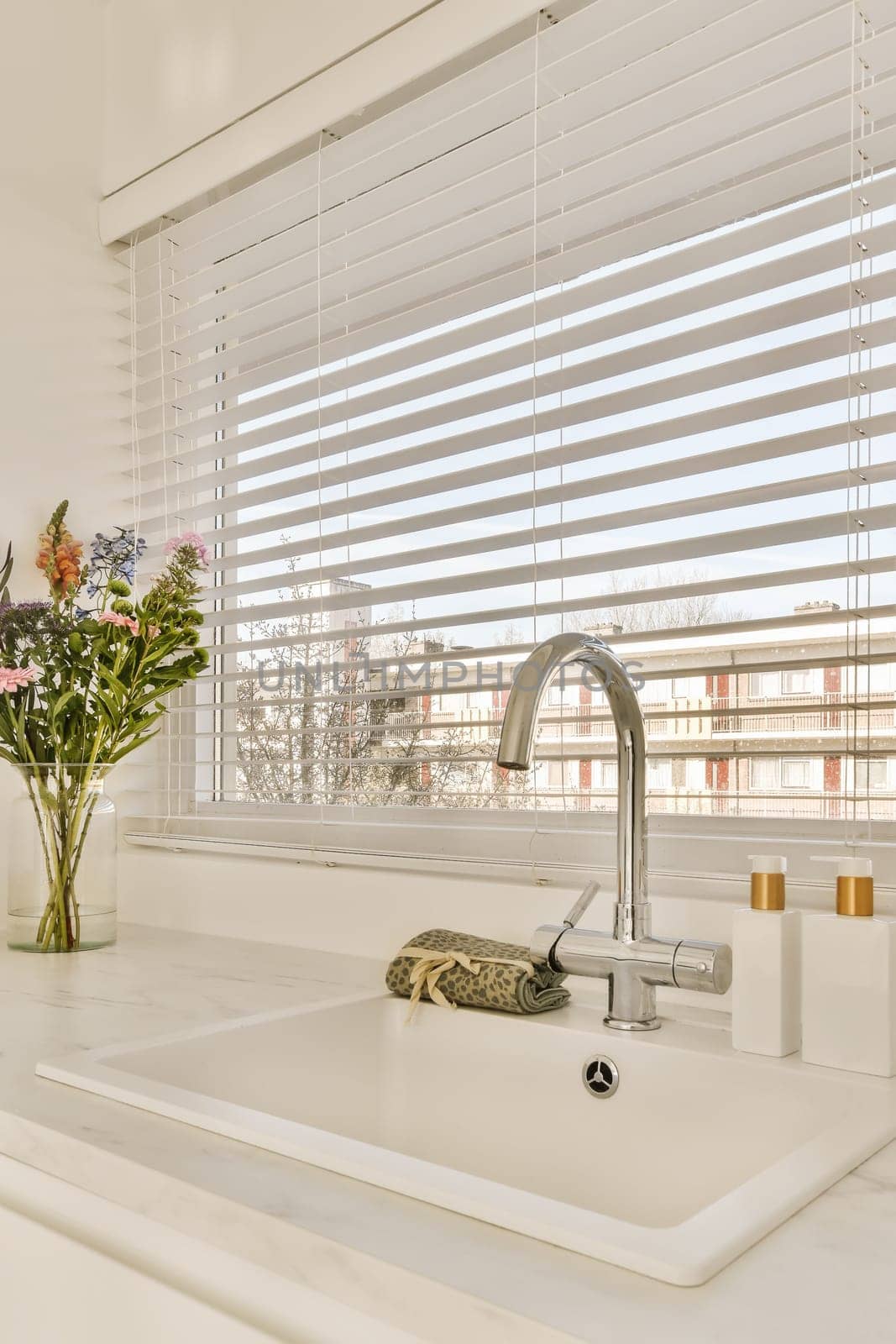 a kitchen sink with a window with white blinds by casamedia