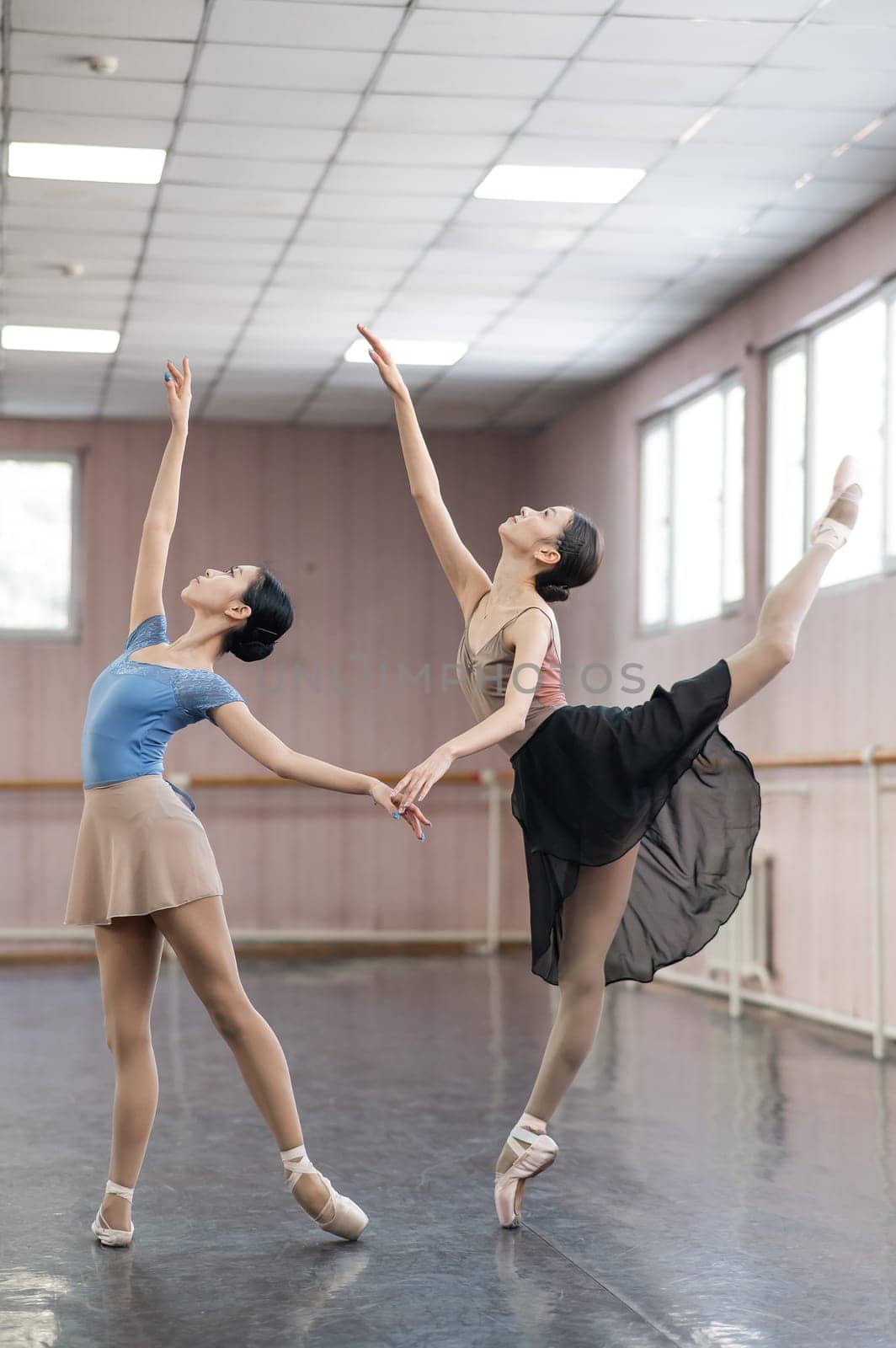 Two Asian ballerinas are dancing in the class