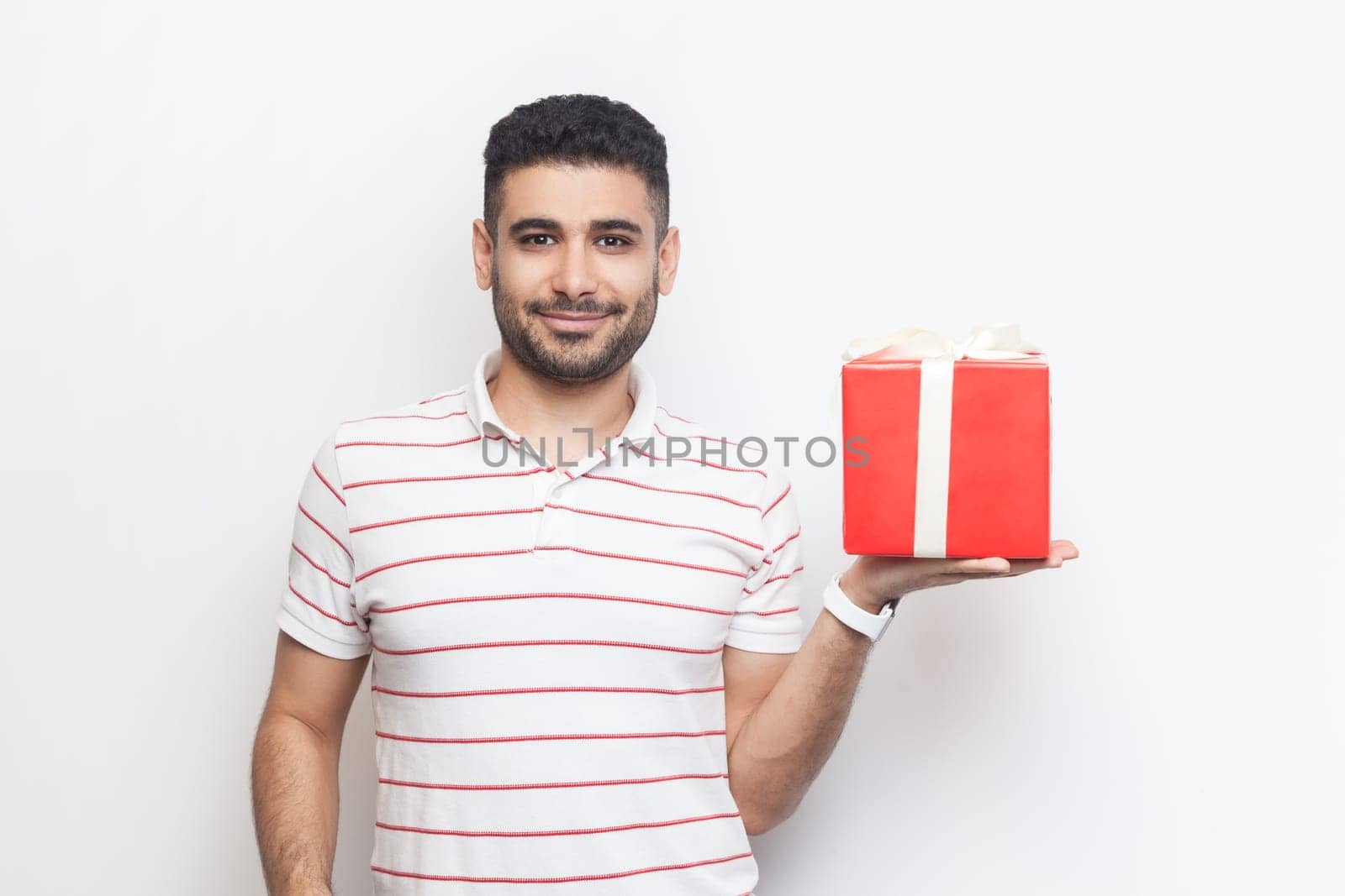 Delighted cheerful handsome bearded man showing red wrapped present box, gift for birthday. by Khosro1