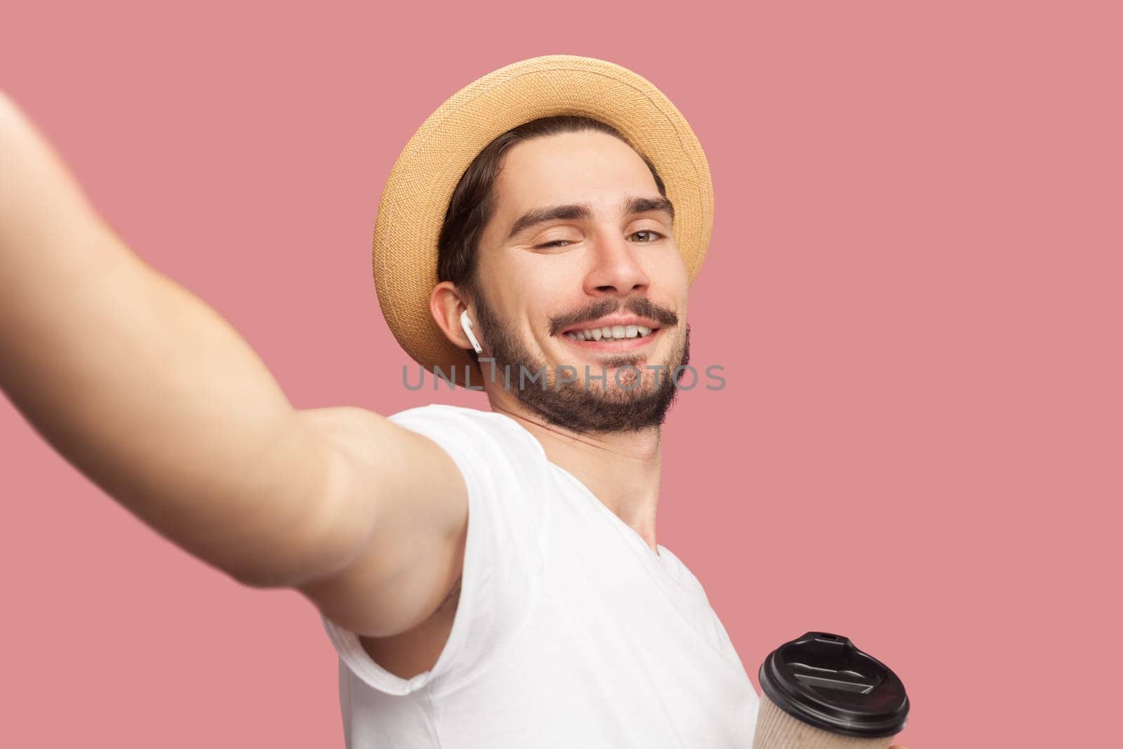Cheerful joyful man in white T-shirt and hat standing drinking coffee looking smiling at camera, POV by Khosro1