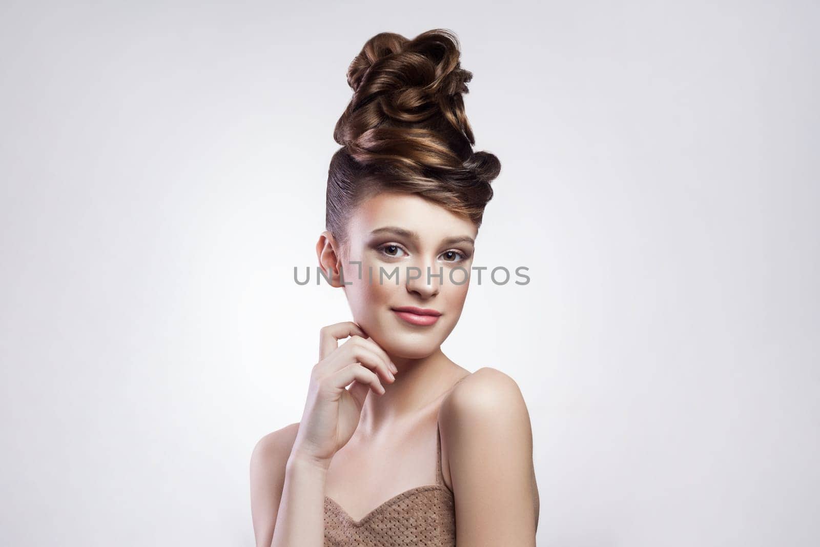 Positive woman with stylish hairdo and makeup, looking at camera with smile, keeps hands under chin. by Khosro1