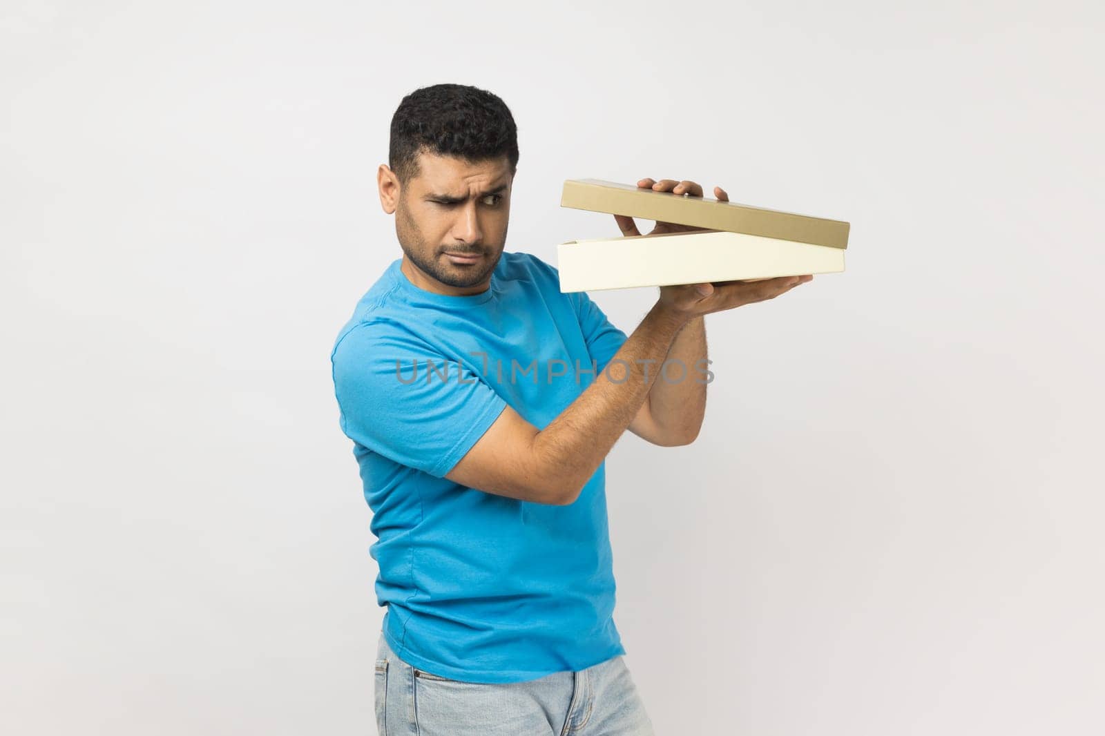 Attractive curious unshaven man holding gift box, looking inside, being interested what he received by Khosro1