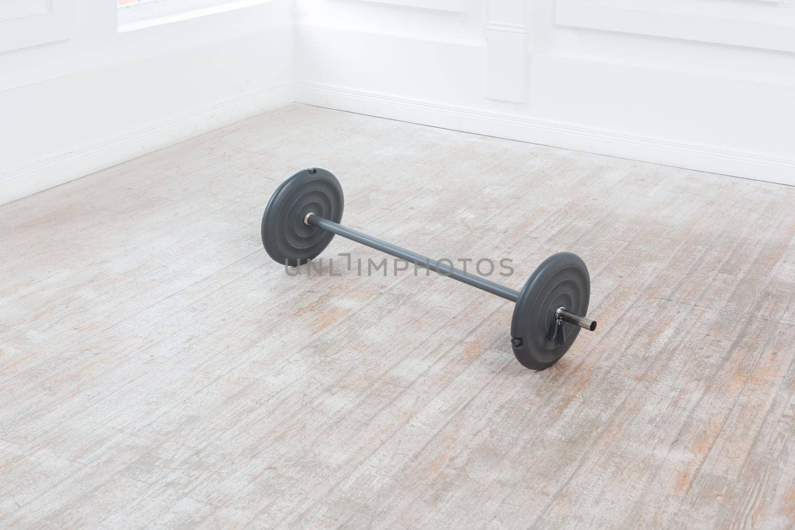 Heavy barbell on floor in gym on white wall background. Sport equipment. Indoor studio shot.