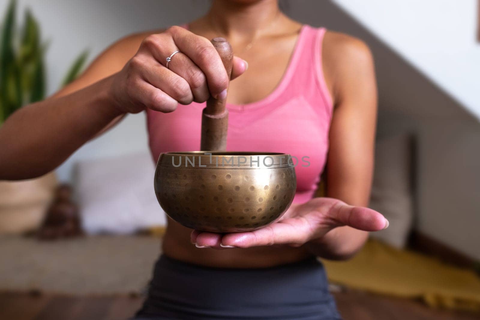 Close-up of unrecognizable woman using Tibetan singing bowl sitting in meditation at home. Spirituality concept.