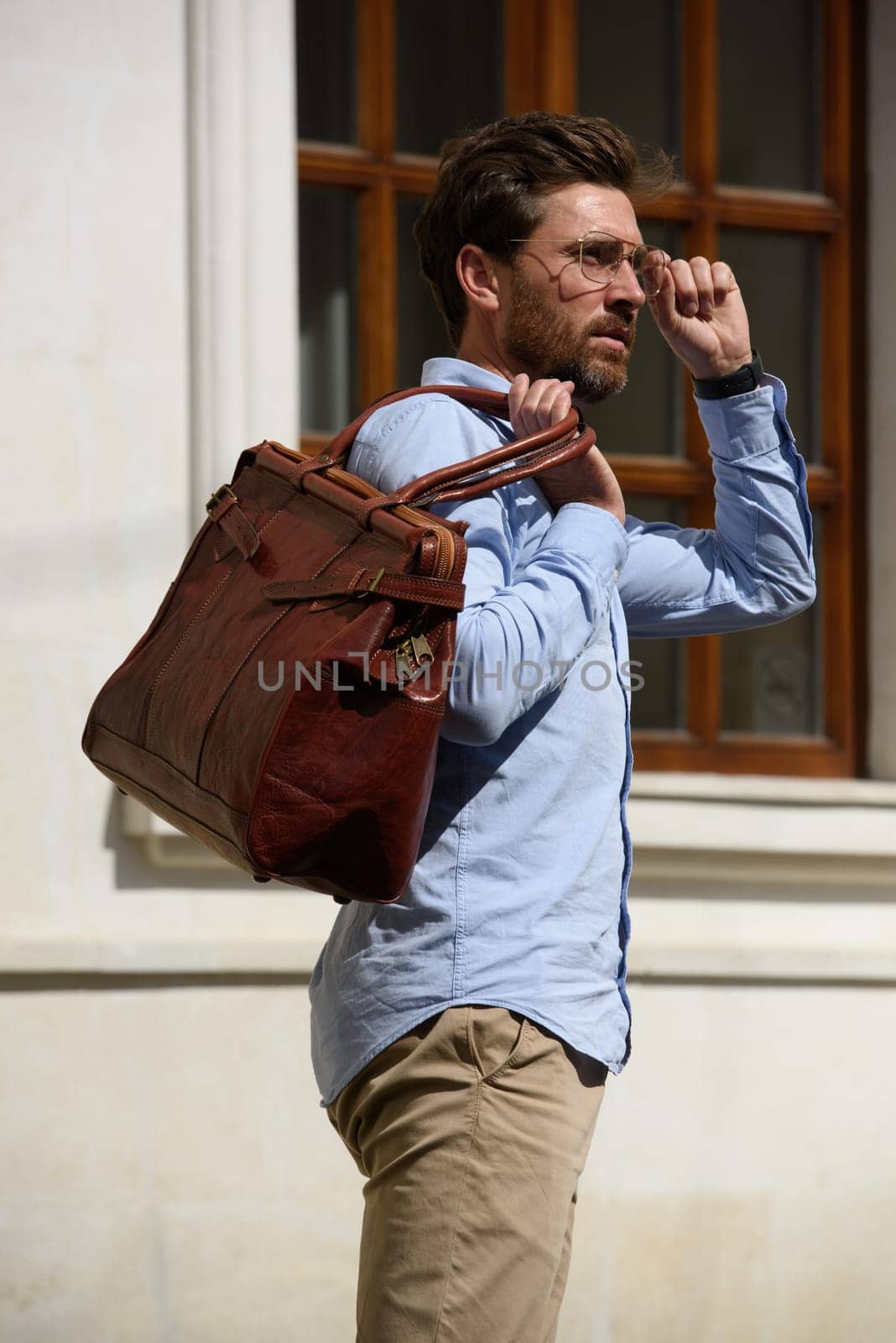 Handsome businessman walking on the street, with luxury leather briefcase. Fashionable style. Street photo