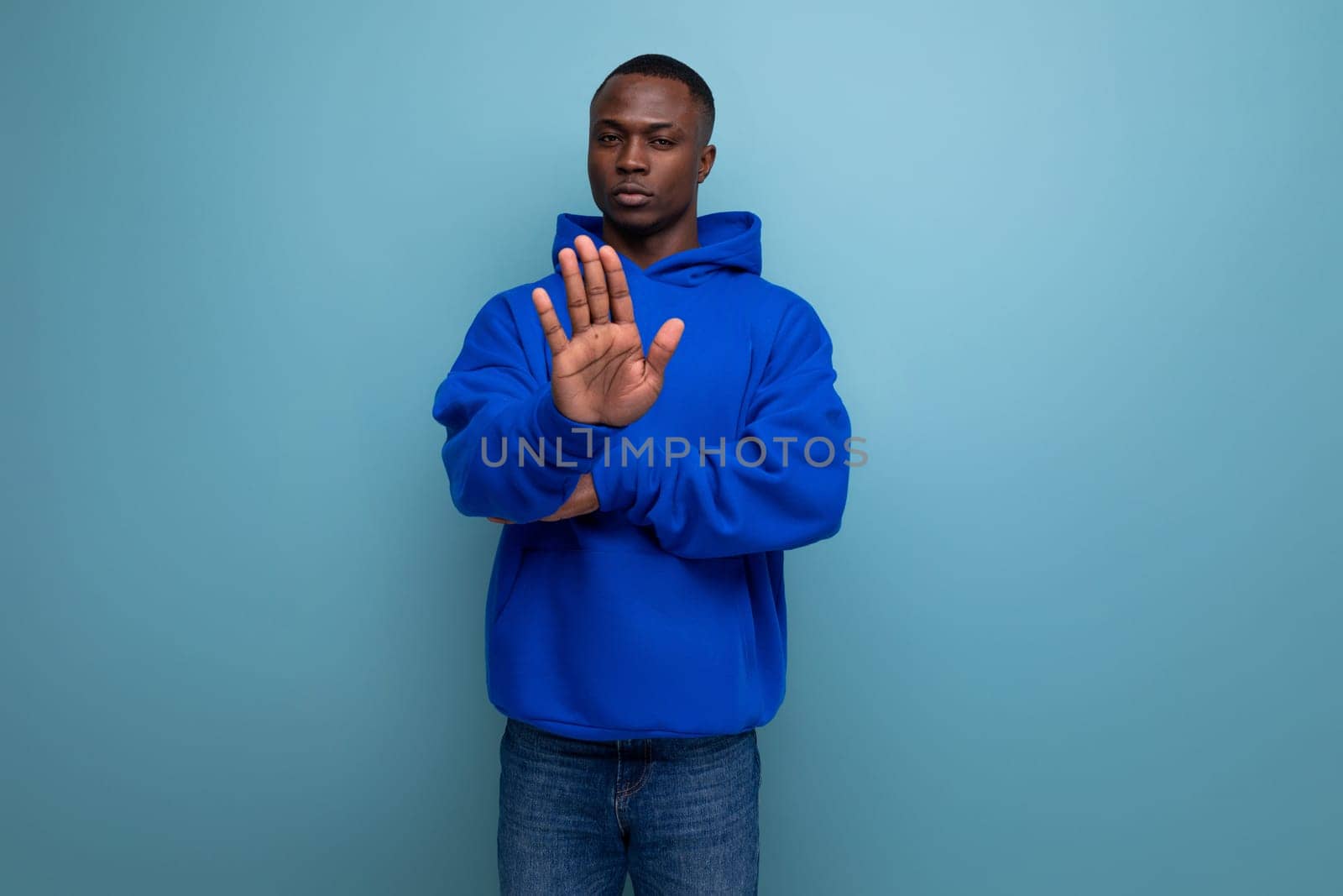 a young african guy in a stylish hoodie demonstrates with his hand on an advertisement on a studio background with copy space.