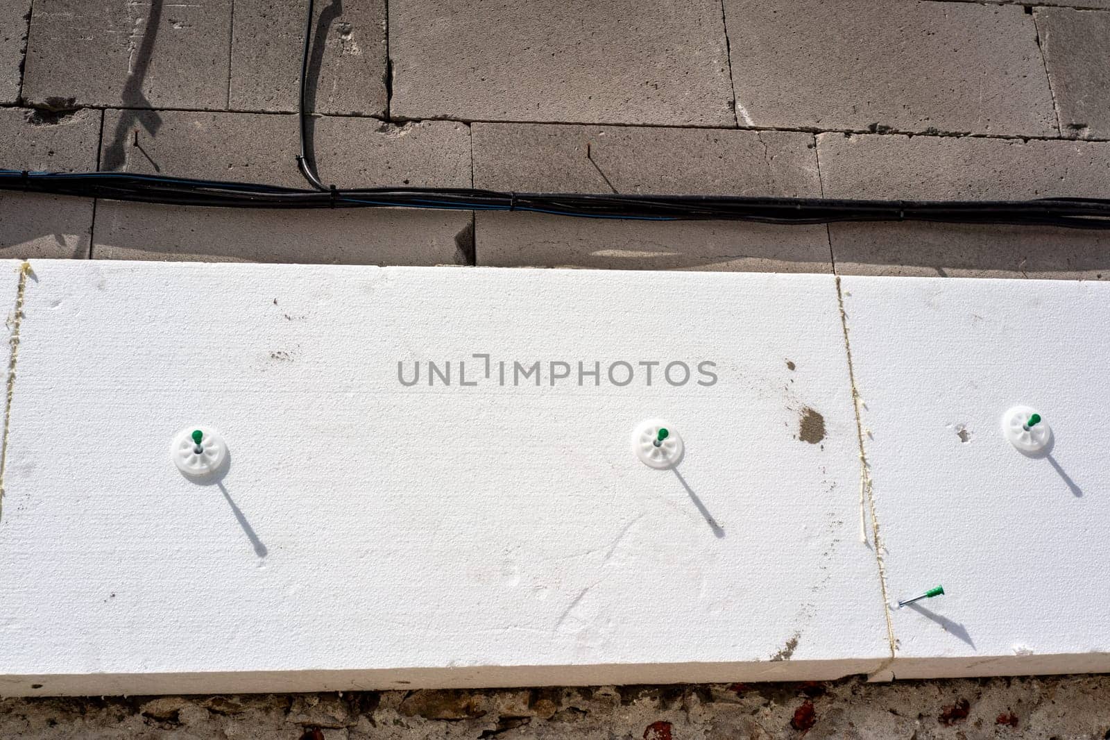 White polystyrene foam board blocks for heat insulation on bare concrete wall at construction site, closeup detail by Ivanko