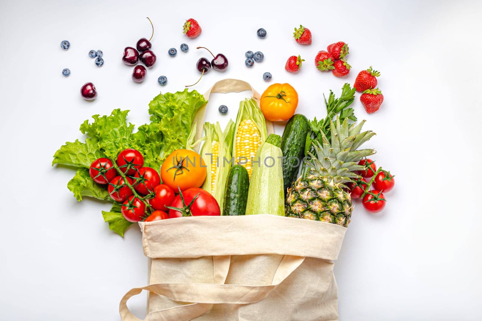 Grocery shopping. Different fresh fruit and vegetables in a textile shopper bag on white background, healthy food from supermarket or delivery concept..