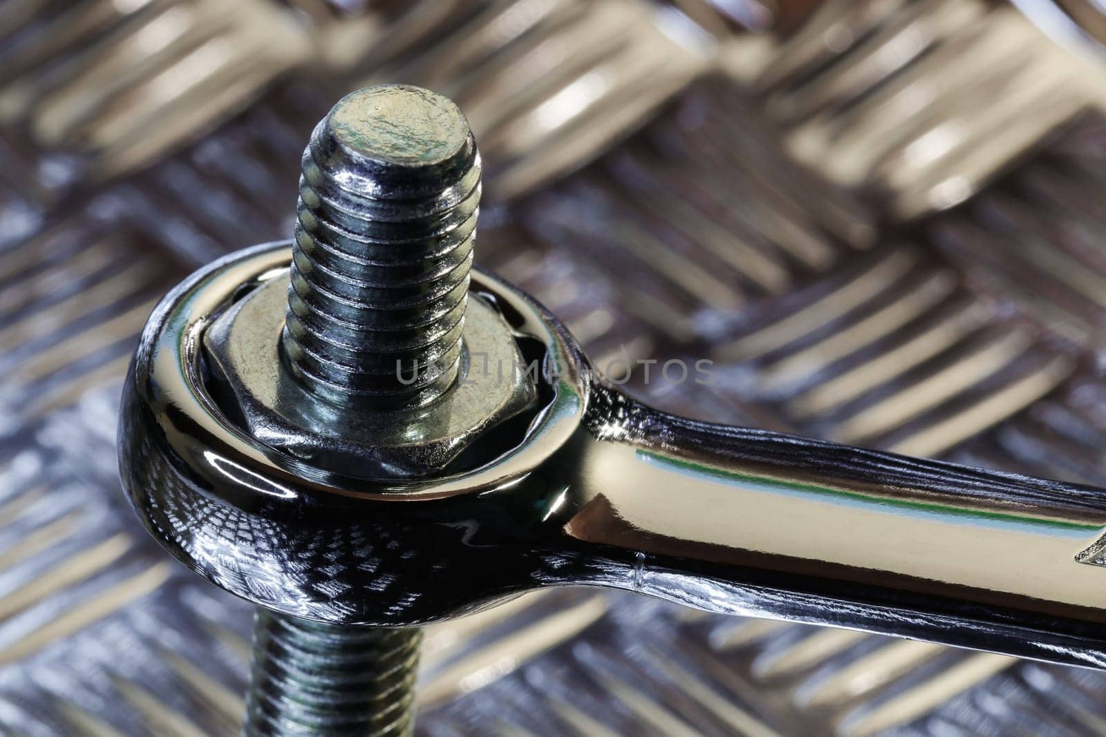 Chrome spanner tightening a steel hex nut to threaded bolt