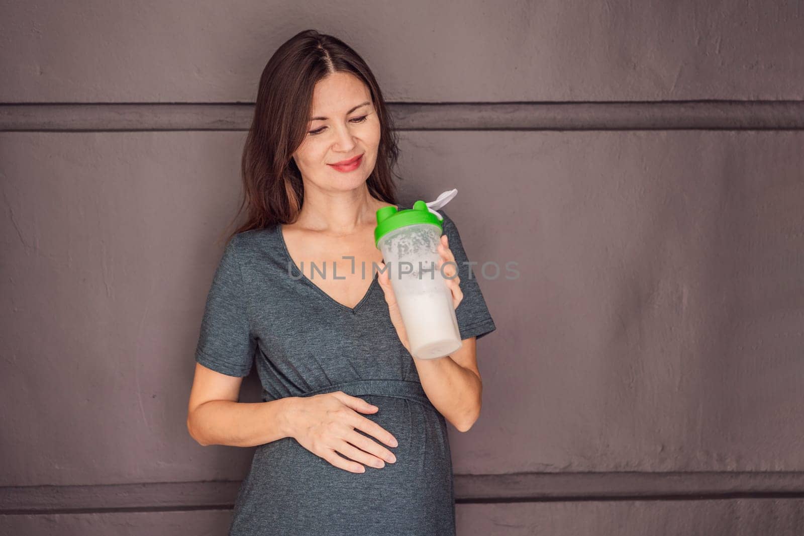 Energetic and fit pregnant woman after 40 enjoying a protein shake for a nourishing boost during her pregnancy journey. Embracing health and wellness for a thriving baby and mom.