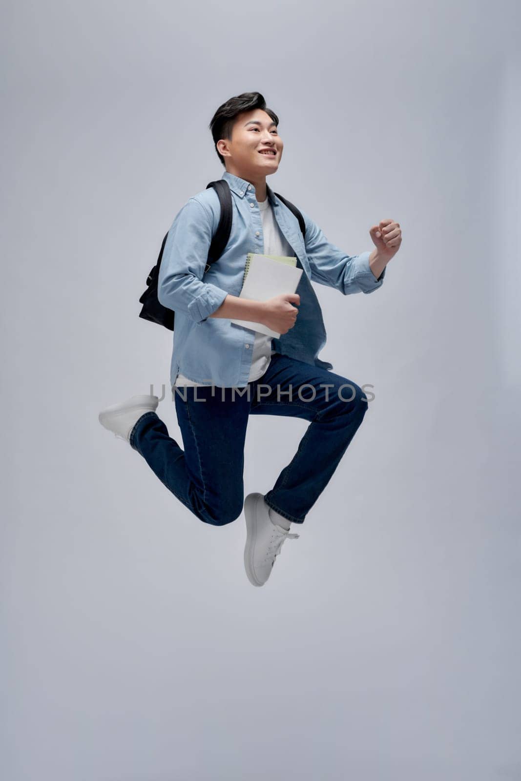 Overjoyed young student man jumping and gesturing happiness isolated on white background by makidotvn