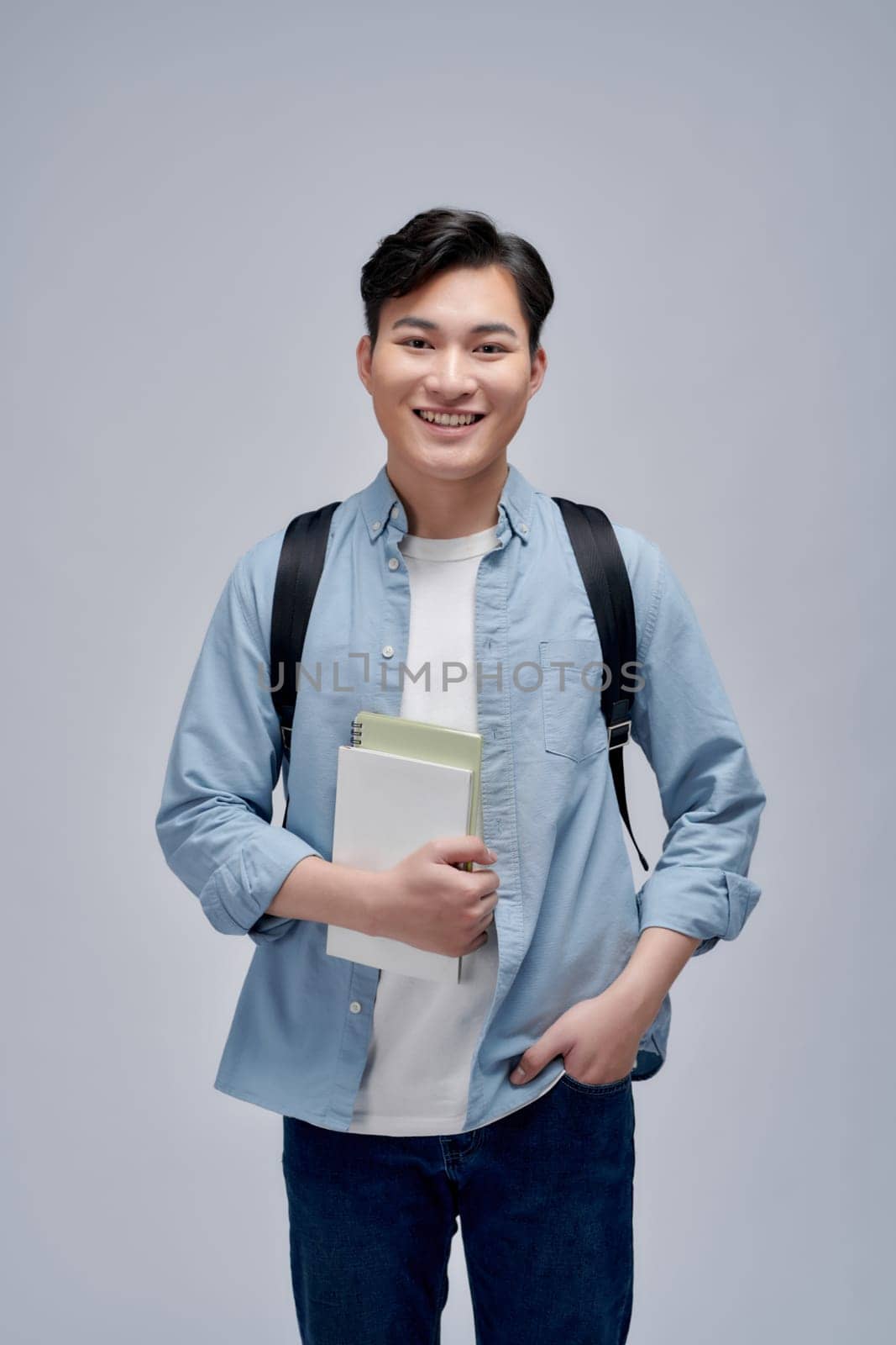Image of content student guy in denim clothes smiling while holding exercise books