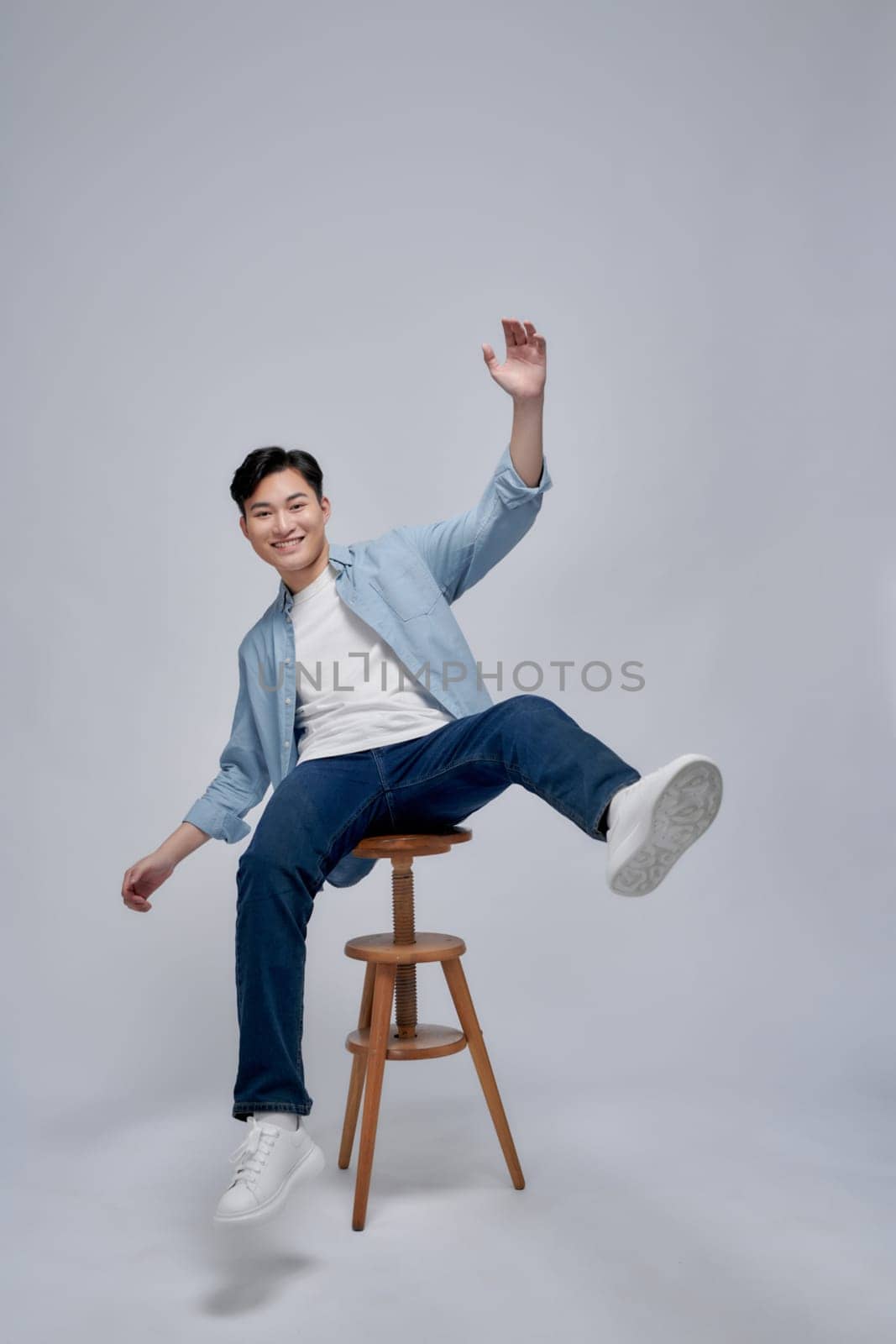 Cheerful joyful man sitting chair hand fist up rejoice empty space isolated on white background by makidotvn