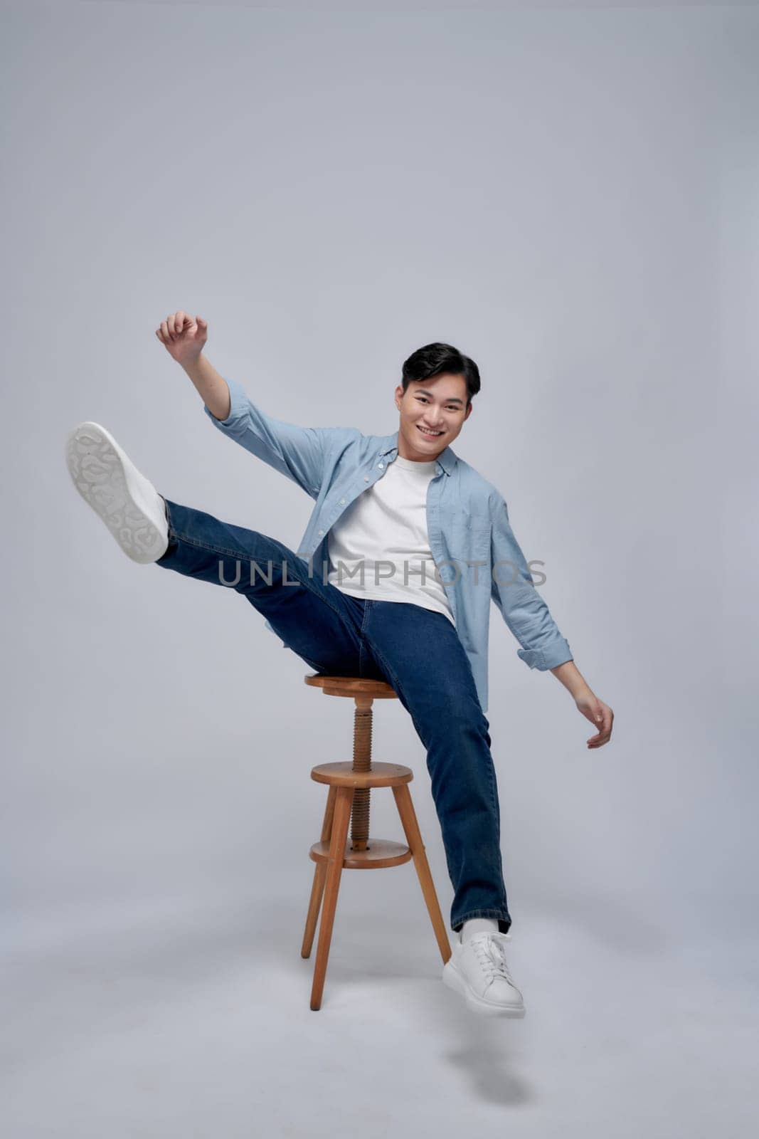 Photo portrait young man smiling sitting on wooden chair isolated on white background by makidotvn